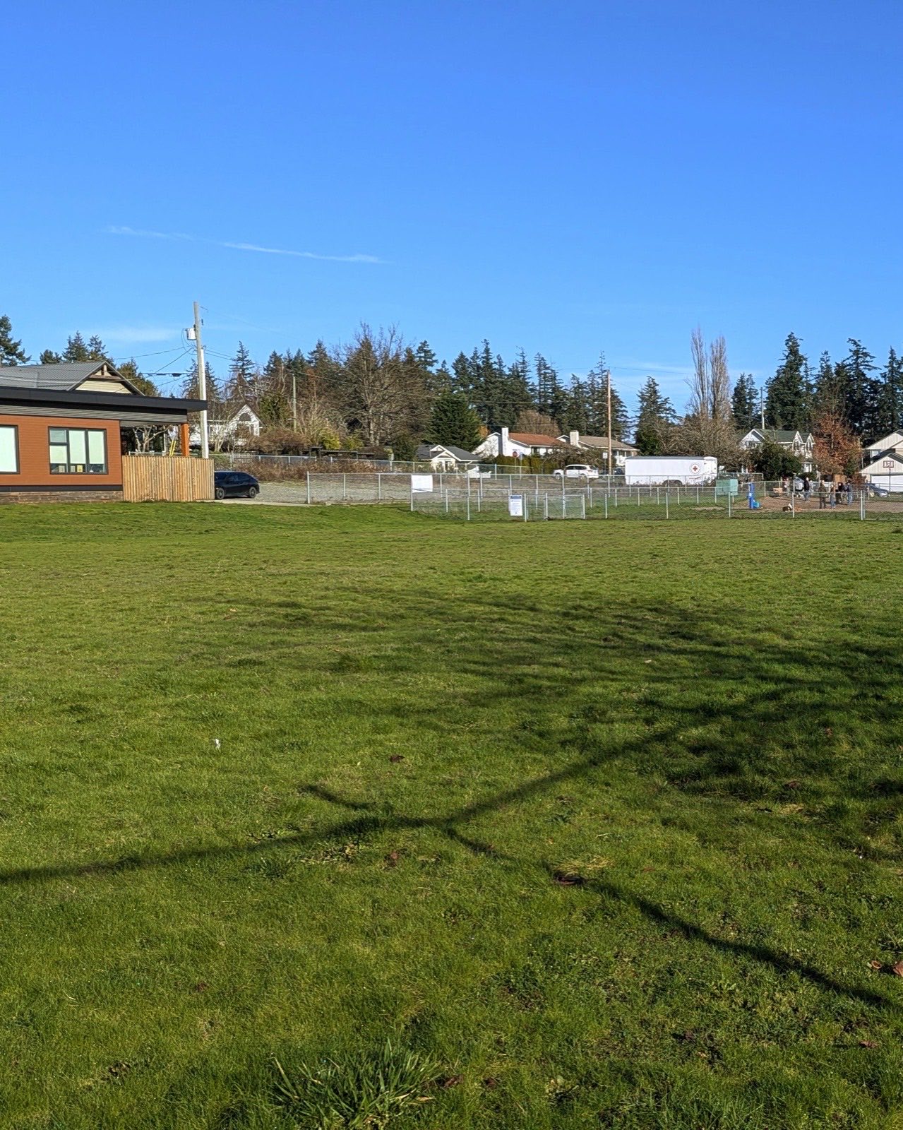 green grassy field with fanced dog park in distance